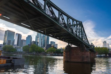 Eiserner Steg köprüsü Frankfurt, Almanya 'daki Main River boyunca uzanır, karmaşık demir işleri, taş iskeleler ve arka planda modern bir silueti vardır..