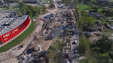 Riga, Letonya 'daki ALEJA alışveriş merkezi yakınlarındaki aktif inşaatın havadan görüntüsü. Turnalar, kazıcılar ve hareket eden araçlar dinamik sahneyi vurguluyor.