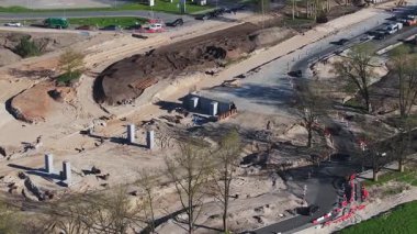 Riga, Letonya 'da aktif bir inşaat alanının hava görüntüsü işçilerin, ağır makinelerin, beton sütunların ve hafif trafiği olan yakınlardaki yolların görüntülerini gösteriyor..