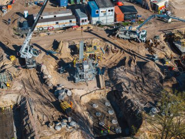 Vinçleri, iskelesi, beton yığınları ve Letonya Riga 'da yüksek görüş mesafesi olan işçileri olan aktif inşaat alanı. Arka planda taşınabilir binalar.