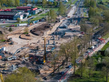 Riga, Letonya 'da etkin inşaat alanı, vinçleri, kazıcıları, temelleri, yapısal sütunları, yakındaki yolları, yeşil alanları ve binaları gösteriyor.