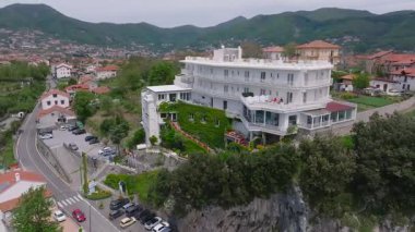 Hava aracı görüntüsü, terasları, yemyeşil otelleri, terasları ve tepelerin yakınındaki dolambaçlı bir yolu ve uzak bir kasaba olan çok katlı bir oteli gösteriyor..