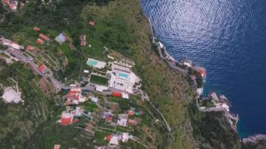 İtalya 'daki Amalfi sahil şeridini süpüren, uçurumları, dolambaçlı yolları, yeşil terasları, dağınık binaları ve ışıldayan mavi denizi gösteren hava manzarası..
