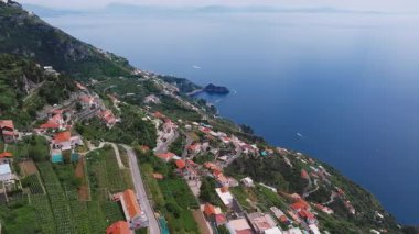 Lüks bir oteli, renkli bir kasabası, dolambaçlı yolları, yeşil uçurumları ve mavi Akdeniz 'de hareket eden bir teknesi olan Amalfi Sahili' nin havadan görünüşü..