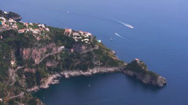 İtalya 'daki Amalfi sahil şeridi hava temizliği, lüks bir otel, dramatik uçurumlar, dolambaçlı yollar, renkli kasaba binaları ve sakin kıyı sularını gösteriyor..