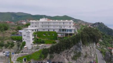 Sarmaşık kaplı, deniz manzaralı, sarmaşık yüzlü, sarmal yolu, ağaçları ve kayalık uçurumları olan lüks bir otelin pürüzsüz havası..