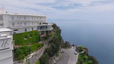 İtalya 'daki Amalfi kıyı şeridinin havadan görünüşü kayalıkları, çatıları, pergoları ve sakin mavi denizde iz bırakan tekneleri gösteriyor..