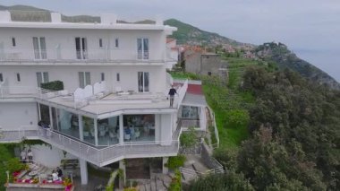 İtalya 'daki Amalfi sahil şeridinin havadan görünüşü kayalık, teraslı tepeler, Amalfi kasabası, kırmızı çatılı binalar ve mavi deniz manzaralı bir otel gösteriyor..
