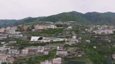 İtalya 'daki Amalfi sahil şeridini süpüren, beyaz ve pastel binalar, yeşillik ve yüksek dağlarla kaplı teras yamaçlarını gösteren,.