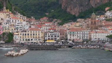 İtalya, Amalfi 'nin havadan görünüşü katedrali, rıhtım güvertesini, uçurumları ve kıyıya yakın sularda süzülen bir tekneyi gösteriyor..
