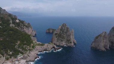Capri, İtalya 'nın havadan görünüşü, Faraglioni kaya oluşumları, yemyeşil, kayalık beyaz binalar ve hareketli mavi deniz..