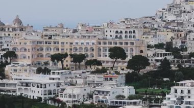 İtalya 'nın Capri kentinin havadan görünüşü. Kemerli camları ve balkonları olan pastel renkli binalar sergileniyor. Etrafı yeşilliklerle çevrili..