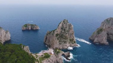 Capri 'nin kıyı şeridi üzerinde düzgün bir hava hareketi, Faraglioni kaya oluşumları, beyaz villalar, yemyeşil ve mavi Tyrhenian Denizi..
