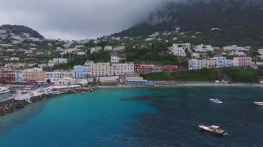 Capri, İtalya 'nın havadan görünüşü, renkli binaları, limanı, turkuaz suları ve yemyeşil tepeleri olan bir kıyı kasabasını gösteriyor..