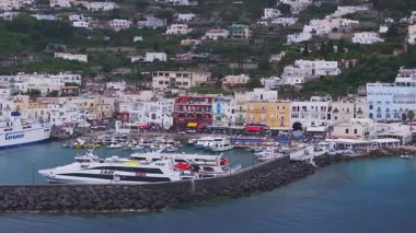 Renkli binalar, limanlı tekneleri, yemyeşil tepeleri ve durgun turkuaz suları olan Capri, İtalya 'da bir sahil kasabasının havadan görünüşü..