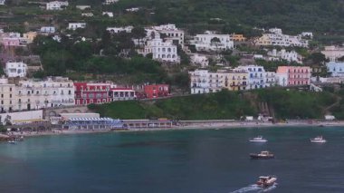 İtalya 'nın Capri kentinin havadan görünüşü, renkli binalar, verimli uçurumlar ve berrak mavi sularda hareket eden veya demirleyen teknelerle dolu bir kıyı kasabasını gösteriyor..