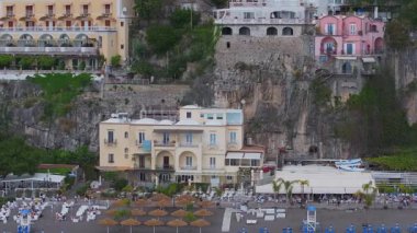 Positano, İtalya 'nın havadan görünüşü, renkli tepe binaları, Santa Maria Assunta Kilisesi, canlı bir sahil ve aşamalı hareketler gösteriyor..