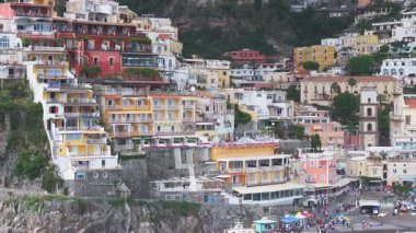 Positano, İtalya 'nın havadan görünüşü, renkli tepe binaları, Santa Maria Assunta Kilisesi ve insan ve şemsiyelerle dolu canlı bir plaj..
