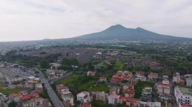 Pompei harabelerinin, sokaklarının ve arka planda Vezüv Dağı 'nın bulunduğu açık alanların yeşil ve modern kenar mahallelerle çevrili havadan görünüşü..