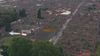 İtalya 'da Pompei' nin havadan görünüşü, amfitiyatrosu, merkezi caddesi, yeşilliği, modern yapıları ve yavaş bir kamera tavası olan harabeleri gösteriyor..