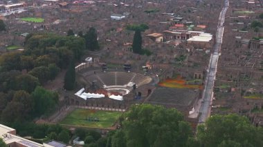 İtalya 'da Pompei' nin yeşil ve antik duvarlarla çevrili harabeler, sokaklar ve amfi tiyatroları üzerinde yavaş bir tavayla hava manzarası.