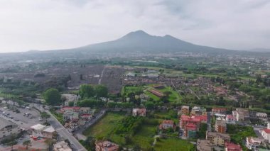 Pompeii 'nin antik harabelerinin, modern binaların ve Vezüv Dağı' nın havadan görünüşü. Kamera yeşillik ve şehir manzaralarında sorunsuzca hareket eder..