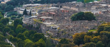 İtalya 'daki Pompei harabelerinin havadan görünüşü taş yapılar, sütunlar, sokaklar ve yeşillikleri gösteriyor. Yapı iskelesi, devam eden koruma çabalarının altını çiziyor.