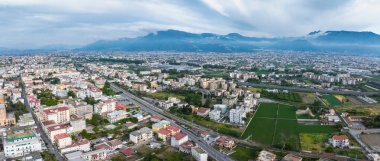 İtalya 'nın Pompei kentsel binaları, yolları, demiryollarını, yeşil alanları ve arka planda bulutlu bir gökyüzünün altındaki dağları gösteren hava perspektifi.