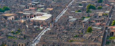 Pompei 'nin İtalya' daki antik harabelerinin havadan görünüşü, korunmuş arkeolojik yapılar arasında taş sokaklar, duvarlar, kısmi çatılar ve yeşillikleri gösteriyor..