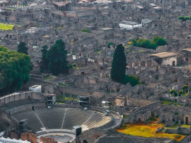 İtalya 'daki Pompei harabelerinin havadan görünüşü yarı dairesel koltuklu amfitiyatronun antik caddeler, binalar ve yeşilliklerle çevrili olduğunu gösteriyor..