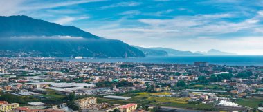 İtalya 'nın Pompei kentsel alanları, yeşil alanlar, kısmen sisli Vezüv Dağı ve ufukta Tyrhenian Denizi yer alıyor..