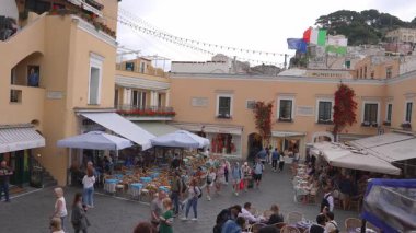 Capri, İtalya 'da canlı bir meydan. Pastel binalar, canlı çiçekler, Municipio' da bayraklar, yürüyen, yemek yiyen ve sohbet eden insanlar..