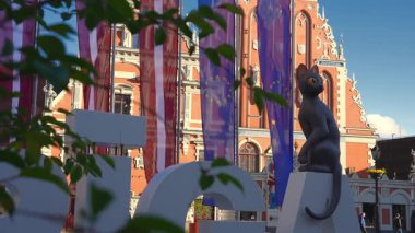 Riga, Letonya 'daki Siyahların Evi' nde süslü detaylar, Riga tabelasında bir kedi heykeli ve dalgalanıp duran AB bayrakları, günlük geçişler..