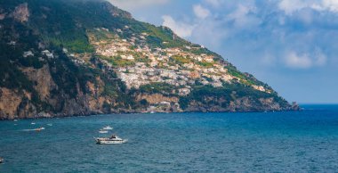 Positano, İtalya 'da, sarp kayalıklardaki pastel renkli binalar, yemyeşil yemyeşil ve Amalfi Sahili boyunca tekne ve yatları bulunan turkuaz sular yer alıyor..