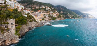 Positano 'nun canlı binaları kayalıklardan Tyrhenian Denizi' ne taşar. Limanda kayalar, kayalık kıyılar, yemyeşil alanlar ve bulutlarla kaplı tepeler vardır..