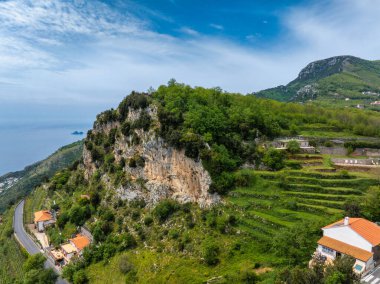 Teraslı tarlaları, kayalık uçurumları, turuncu çatılı binaları, dolambaçlı bir yolu ve uzak bir adası olan Tyrhenian Denizi 'nin havadan görünüşü..