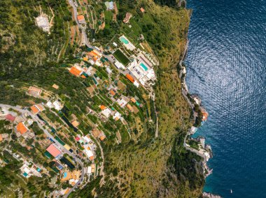 Teraslı tepeler, renkli binalar, havuzlu lüks bir otel, dolambaçlı yollar ve Tyrhenian Denizi 'nin yer aldığı Amalfi, İtalya' nın hava görüntüleri..