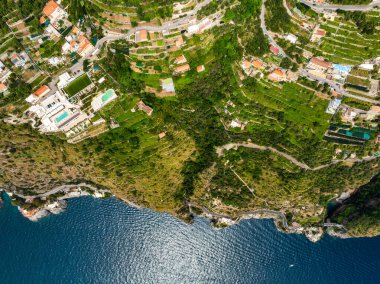İtalya 'daki Amalfi Sahili' nin teraslı yamaçları, lüks villaları, virajlı yolları ve Tyrhenian Denizi 'ne inen kayalıkları gösteren hava görüntüsü..