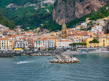 İtalya 'nın Amalfi Sahili' ndeki Amalfi kasabasında çağlayan renkli binalar, Amalfi Katedrali, küçük bir liman, uçurumlar ve Tırren Denizi yer alıyor..