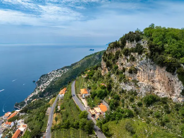 İtalya 'daki Amalfi Sahili' nin havadan görünüşü yeşil, teraslı üzüm bağları, turuncu çatılı binalar, dolambaçlı yollar ve Tyrhenian Denizi 'ndeki uçurumları gösteriyor..