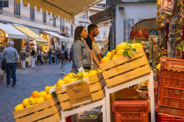 İtalya 'nın Amalfi kentindeki hareketli bir pazarda el yazısı, kaldırım taşı sokakları, dükkanlar ve bakınan insanlarla dolu sandıklar dolusu büyük limon bulunuyor..