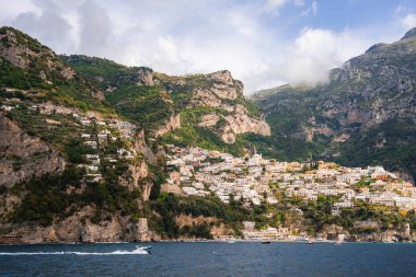 Positano 'nun renkli binaları sarp kayalıklardan aşağı, yeşil tepeler, engebeli kayalıklar ve küçük teknelerle çevrili Tyrhenian Denizi' ne dökülüyor..