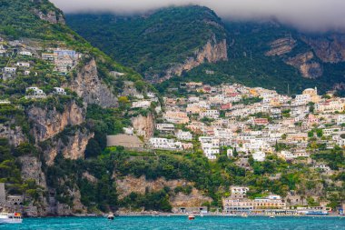 Positano, İtalya 'da renkli binalar turkuvaz suları, yemyeşil yemyeşil, engebeli kayalar ve Tyrhenian Denizi boyunca uzanan teknelerle kayalıklardan aşağı dökülüyor..