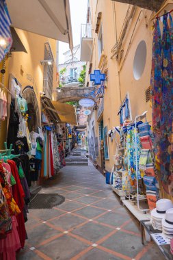 Positano, İtalya 'daki dar sokaklar giysi ve hediyelik eşya satan dükkanlarla dolu. Sıcak tonlu binalar ve eczane tabelaları benzersiz detaylar ekler.