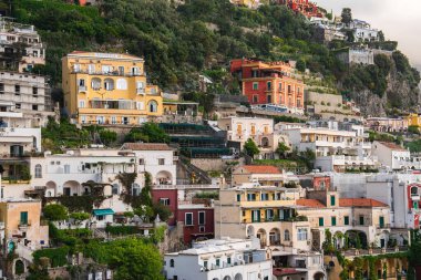 Positano, İtalya manzarası, sarp kayalıklardan dökülen renkli binalar, kemerli pencereler, balkonlar ve teraslı bahçeli yemyeşil alanlar..