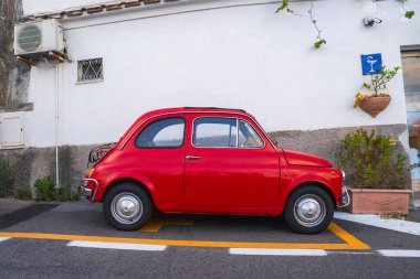 Kırmızı bir Fiat 500, küçük bir penceresi, demir parmaklıkları, bir kliması ve Positano, İtalya 'da saksı bitkileri olan beyaz bir sıva duvarının yanına park edilmiştir..