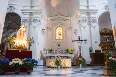 Ravello, İtalya 'da bir kilisenin içinde, içinde dini bir heykel, haç, Bakire Meryem heykeli, mumlar ve çiçeklerle süslenmiş bir sunak var..