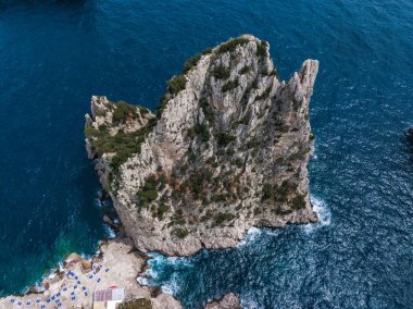 Çevresi Akdeniz sularıyla çevrili, tabanda sandalye ve şemsiyelerin yer aldığı küçük bir plaj alanı olan yüksek kayalık bir oluşum..