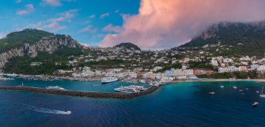 Capri Adası 'ndaki Marina Grande' de lüks yatlar, renkli binalar, yemyeşil tepeler, kayalık uçurumlar ve yumuşak renkli bulutların altındaki turkuaz sular yer alıyor..