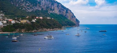 Capri Adası 'nın yemyeşil, renkli sahil binaları ve Amalfi Sahili yakınlarındaki Akdeniz' deki tekneleri olan yüksek uçurumları..